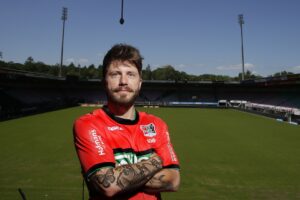 Mand iført rød trøje med armene over kors