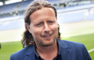 Bo Henriksen iført blå jakke og med sit lange hår