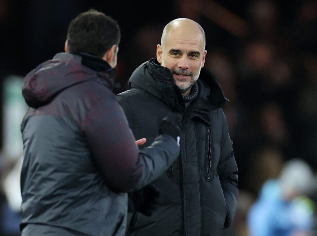 Pep Guardiola i sin sorte jakke trykker hånden med en anden mand.