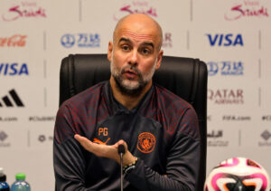 Guardiola sidder med en fremstrakt hånd