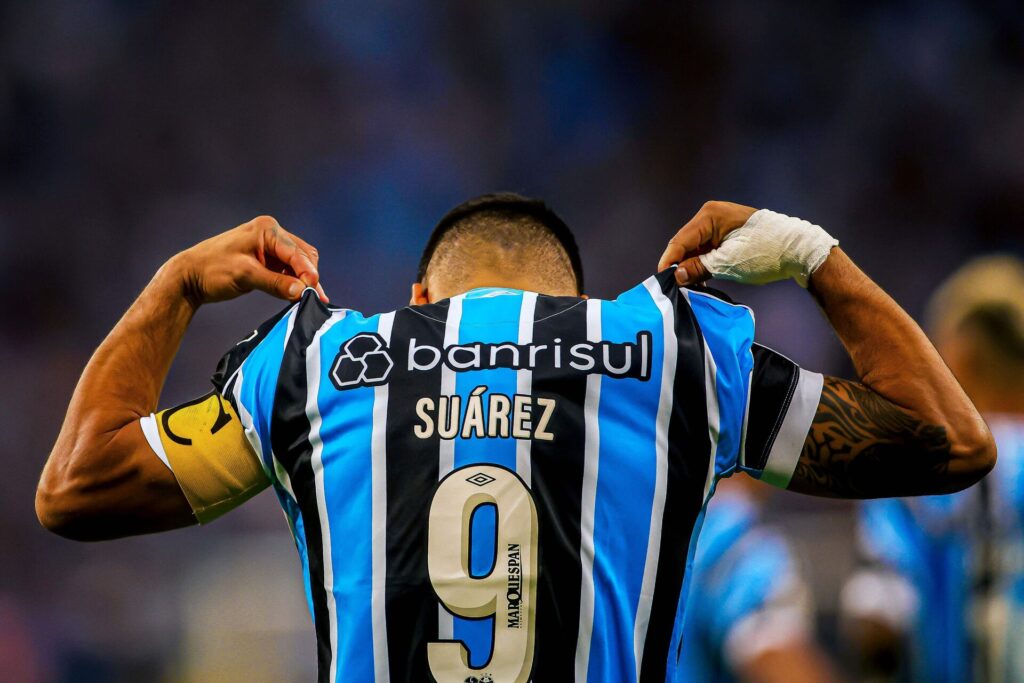 Luis Suaraz løfter i den blå/sorte trøje med armbånd på armen.