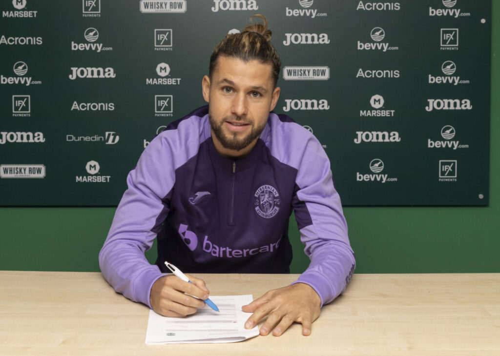 Emiliano Marcondes sidder og underskriver kontrakt for Hibernian