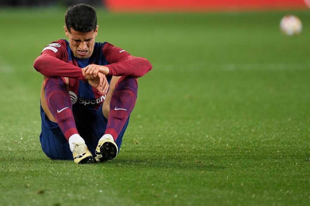 Joao Cancelo sidder ned på græsset under Champions League-kampen mellem FC Barcelona og Napoli.
