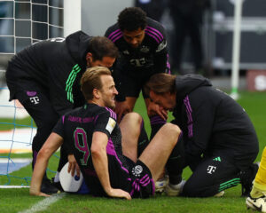 Harry Kane sidder på græsset og modtager behandling for en ankelskade.