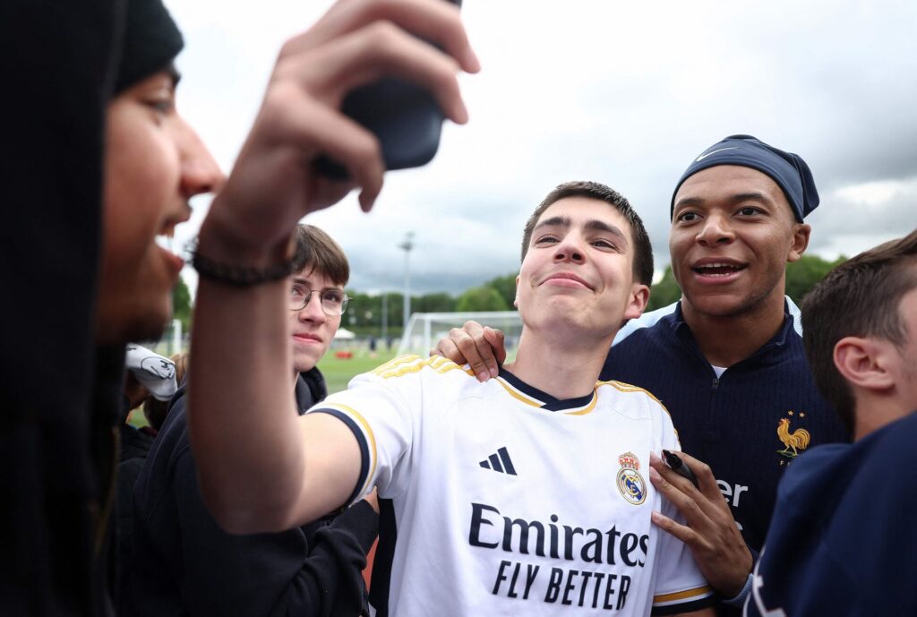 Kylian Mbappé poserer med en fan iklædt en Real Madrid-trøje under Frankrigs træning.