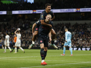 Erling Haaland fejrer en scoring mod Tottenham med Rodri på ryggen.