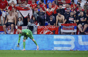 Kasper Schmeichel samler ølkrus op, som de serbiske fans har kastet efter ham under kampen mellem Danmark og Serbien ved EM 2024.