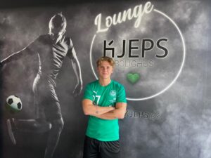 Patrick Allentoft iført grøn Næstved-trøje foran loungevæg