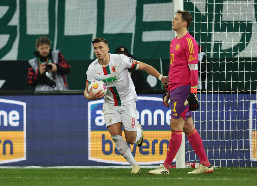 Ermedin Demirovic løber med bolden i hænderne forbi Manuel Neuer, som ser skuffet ud.