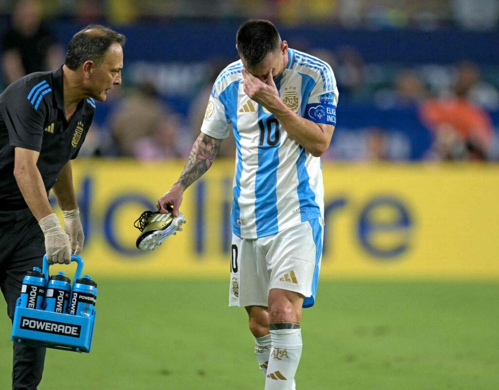 Lionel Messi tager sig til ansigtet, mens han trasker ud af banen med en skade i finalen for Argentina