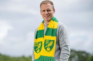 Hoff Thorup spejder ind i kameraet med Norwich-halstørklæde om halsen