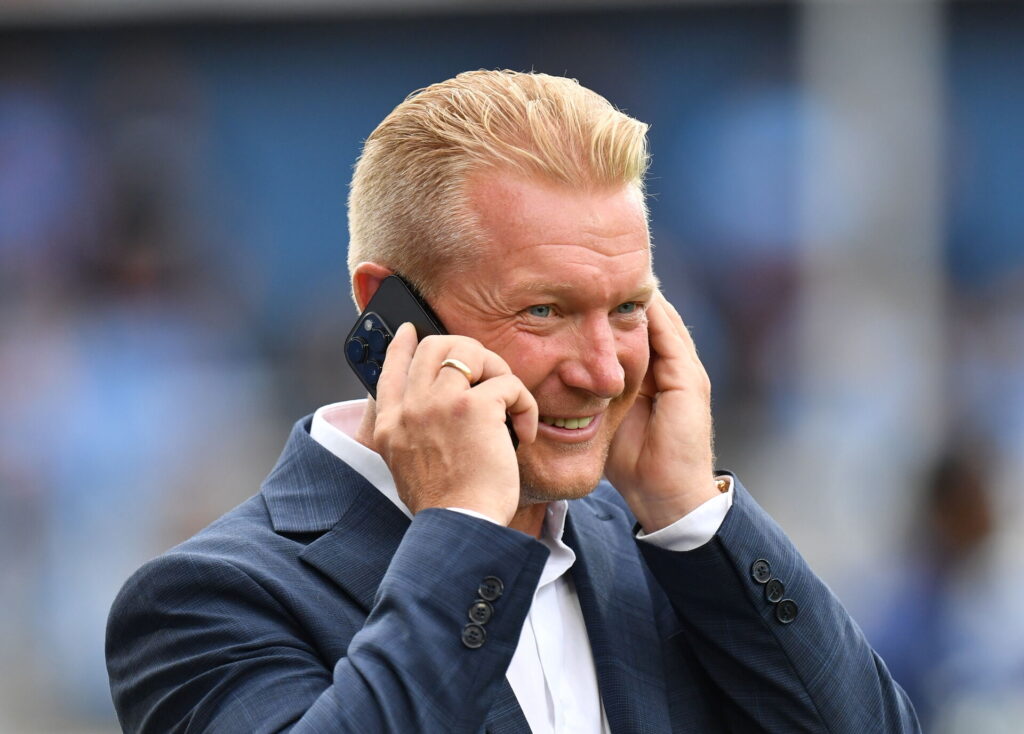 Søren Pedersen smiler mens han taler i telefon på Randers' stadion