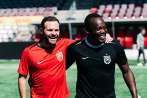 Juan Mata står sammen med Michael Essien og smiler på Right to Dream Park.