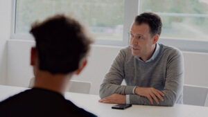 Mikkel Hemmersam sidder ved et bord med en iPhone liggende foran sig.