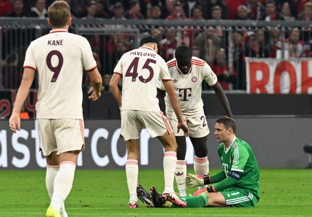 Manuel Neuer sidder ned på græsset omringet af holdkammerater.