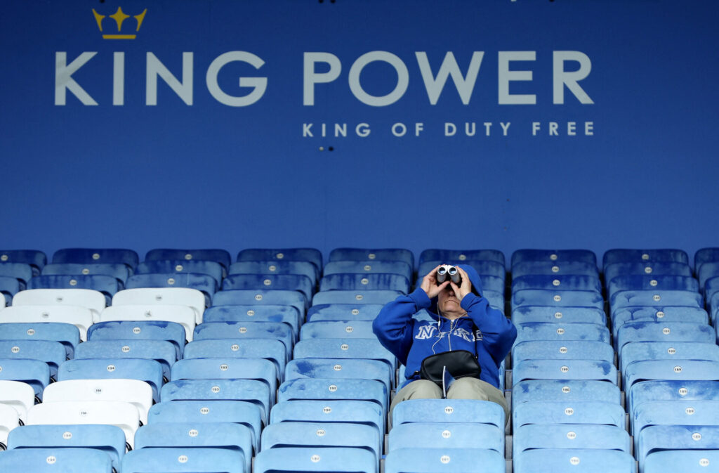 En Leicester-fan sidder med kikkert på stadion.