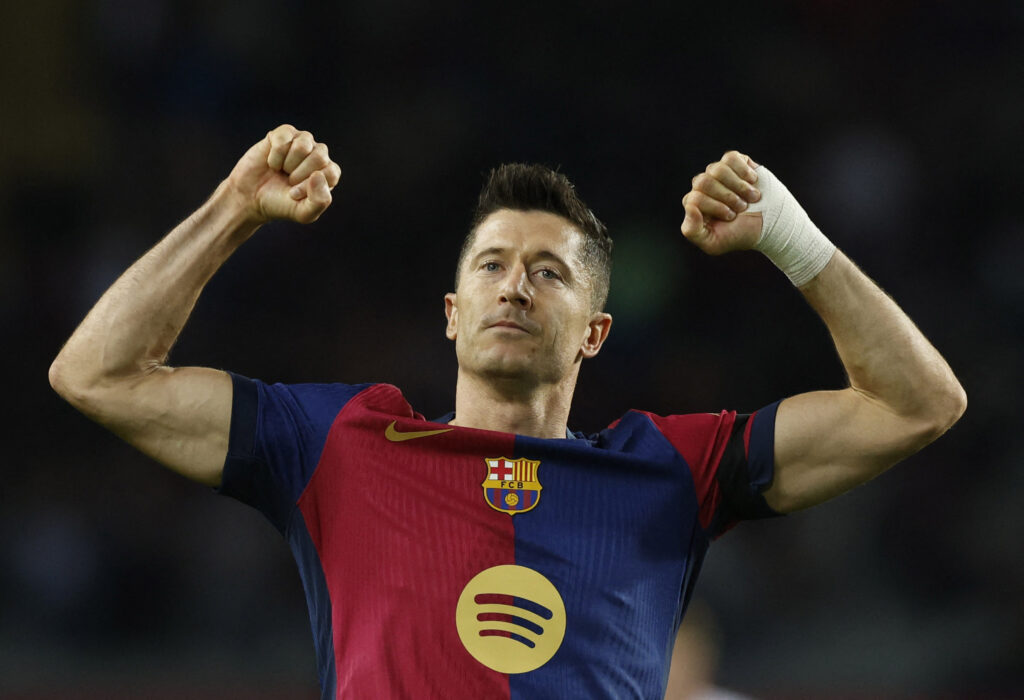 Robert LEwandowski i FC Barcelona-trøje rækker arme i vejret.