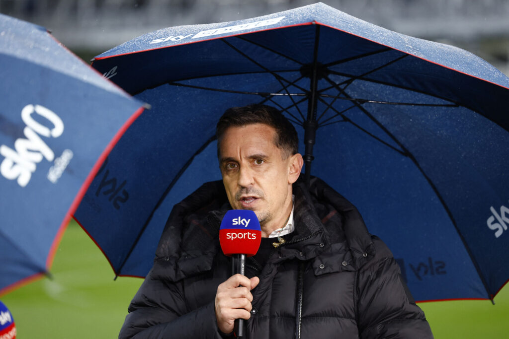 Gary Neville står med en mikrofon under en paraply.