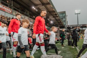 German Onugkha med en bolddreng i hånden under indløb.