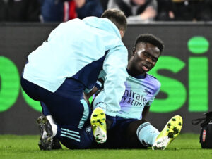 Bukayo Saka sidder på banen og modtager behandling.