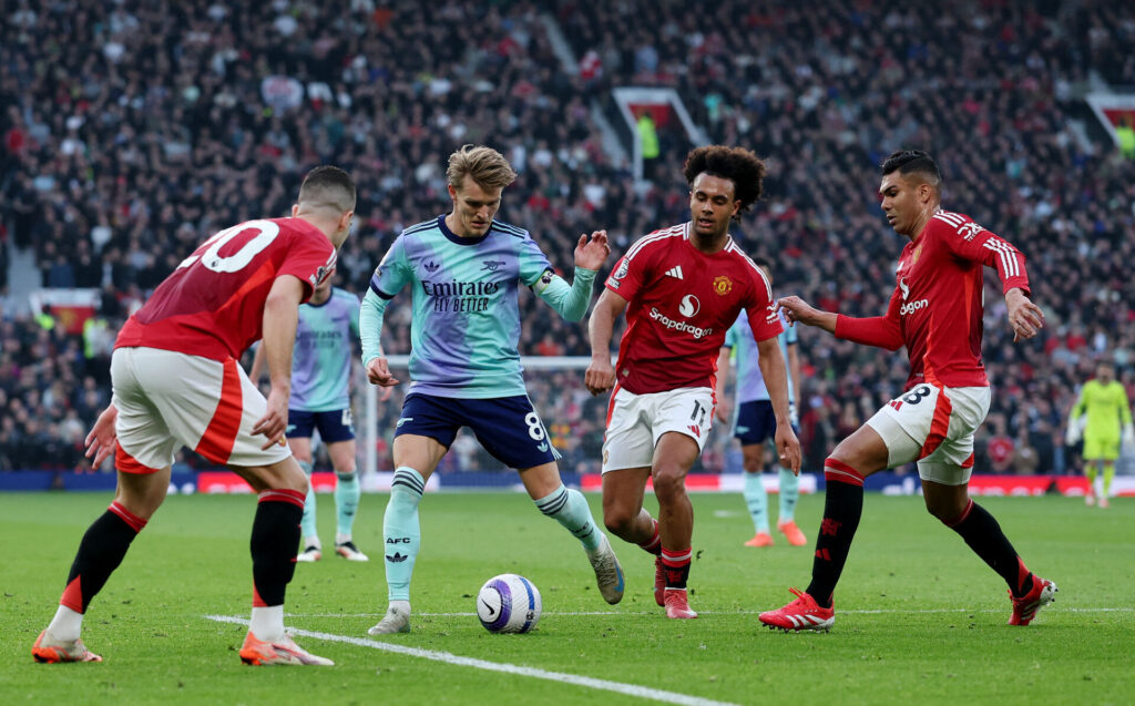 Arsenals Martin Ødegaard dribler med bolden mellem tre Manchester United-spillere.