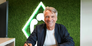 Horst Steffen med et stort smil foran Werder Bremen logo.
