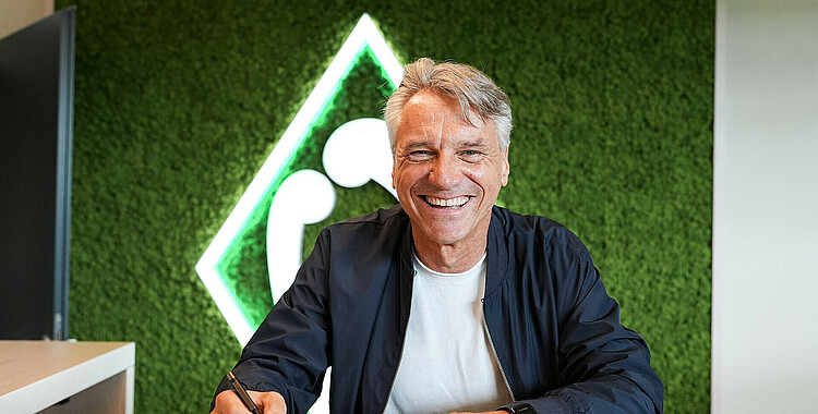 Horst Steffen med et stort smil foran Werder Bremen logo.