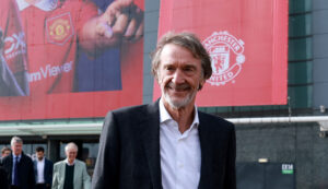 En smilende Sir Jim Ratcliffe foran Manchester Uniteds Old Trafford.
