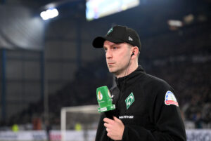 Werder Bremen cheftræner Ole Werner med mikrofon i hånden.