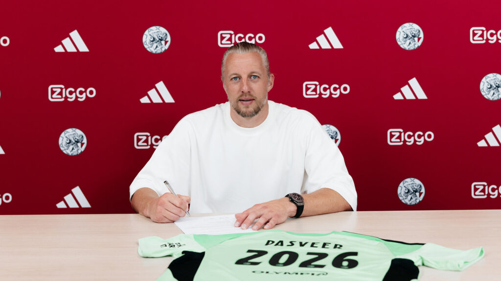 Remko PAsveer skriver under på en kontrakt med en trøje med skriften 2026 ligger på bordet.