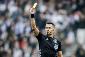 Sandi Putros fløjter og giver gult kort.