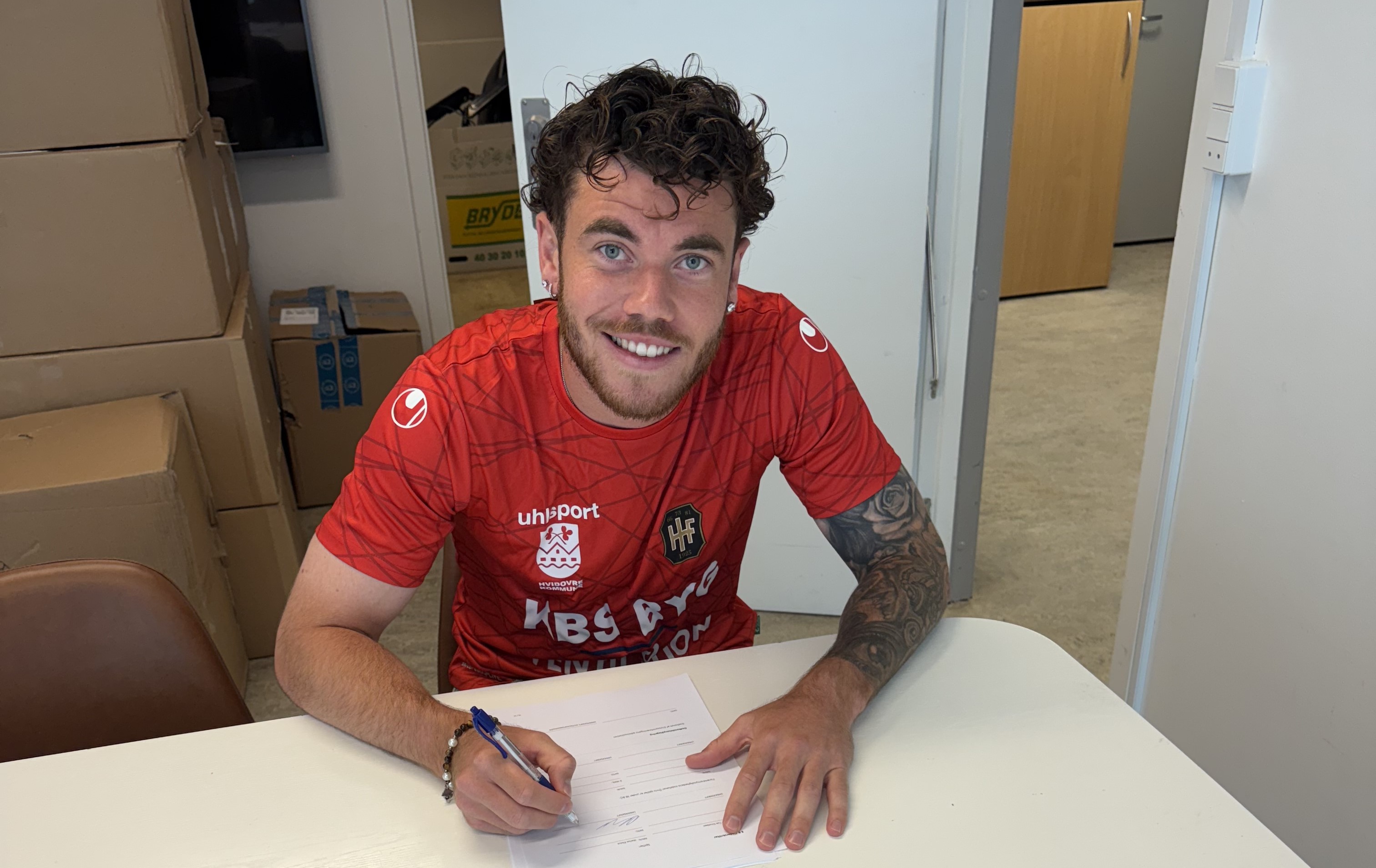 Marius Elvius skriver under på en kontrakt, der ligger på et hvidt bord i Hvidovre.