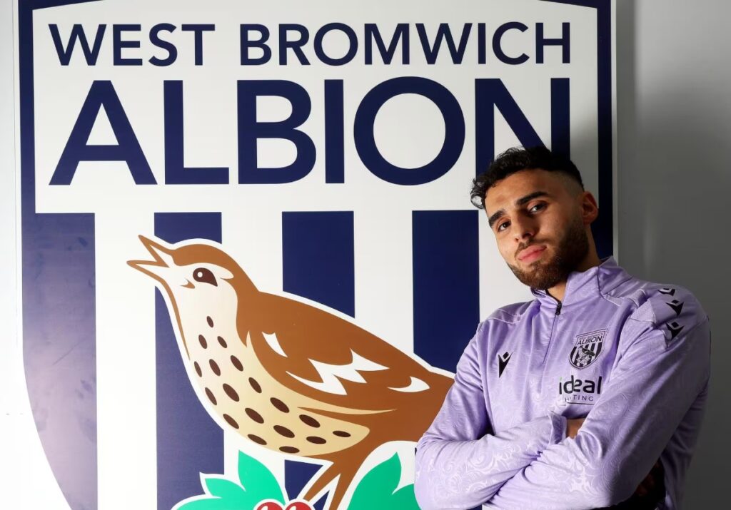 Tammer Bany med korslagte arme foran et WBA logo.