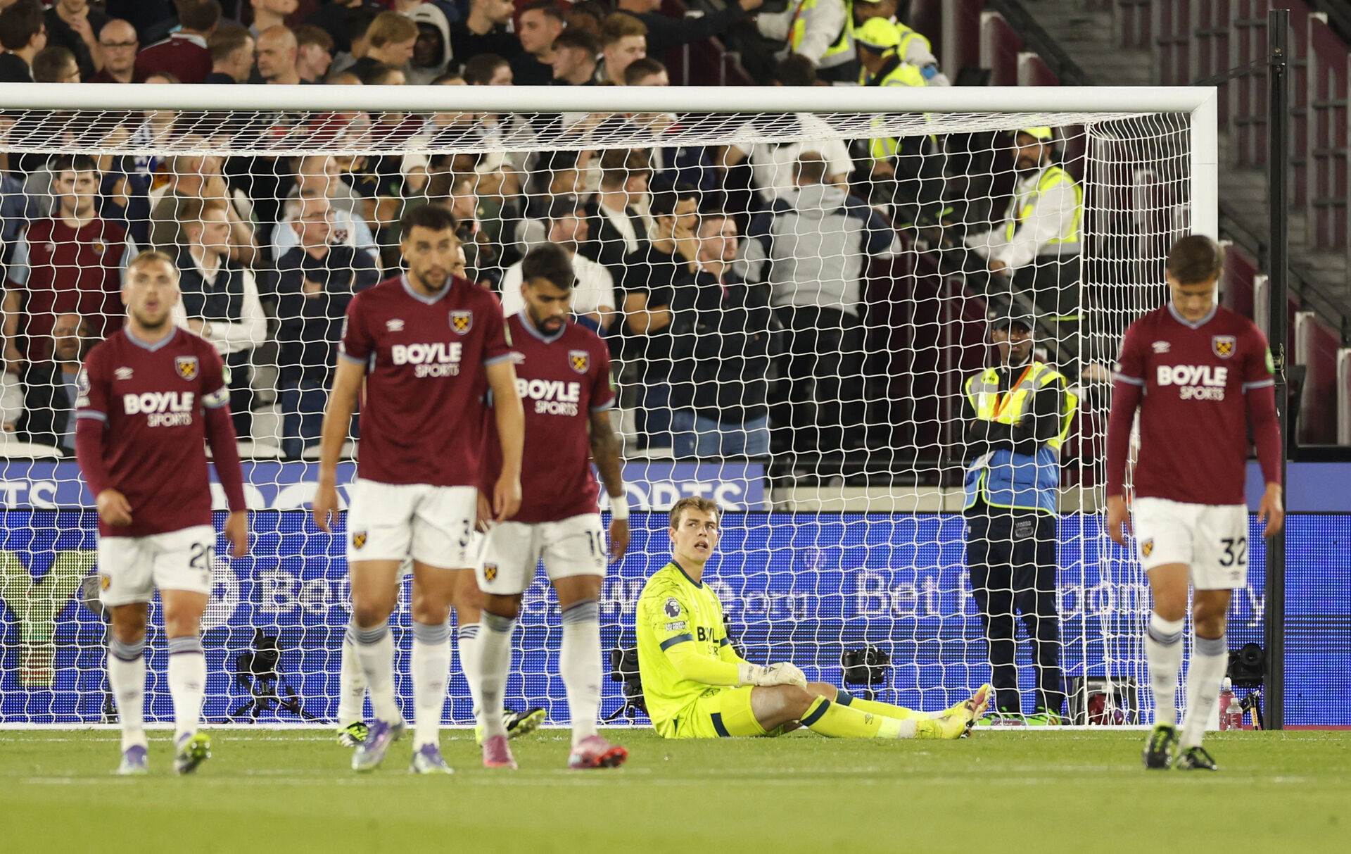 Mads Hermansen sidder på græsset og kigger på sine holdkammerater fra West Ham.