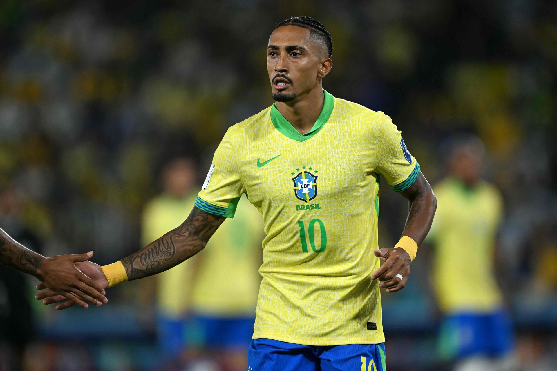 Raphinha klapper en medspiller i hånden under en landskamp for Brasilien