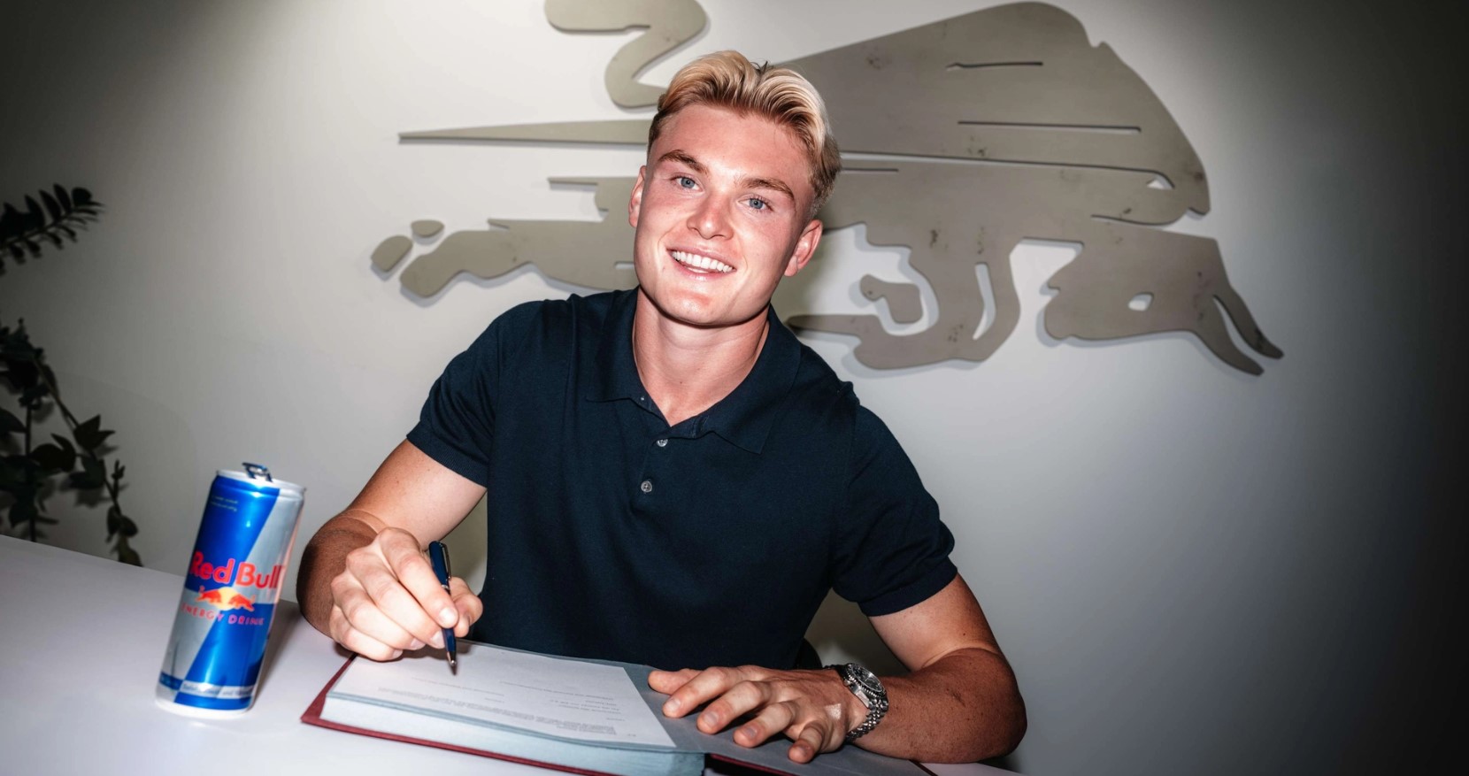 Conrad Harder skriver under på en kontrakt i Leipzig med en Red Bull dåse foran sig på bordet.