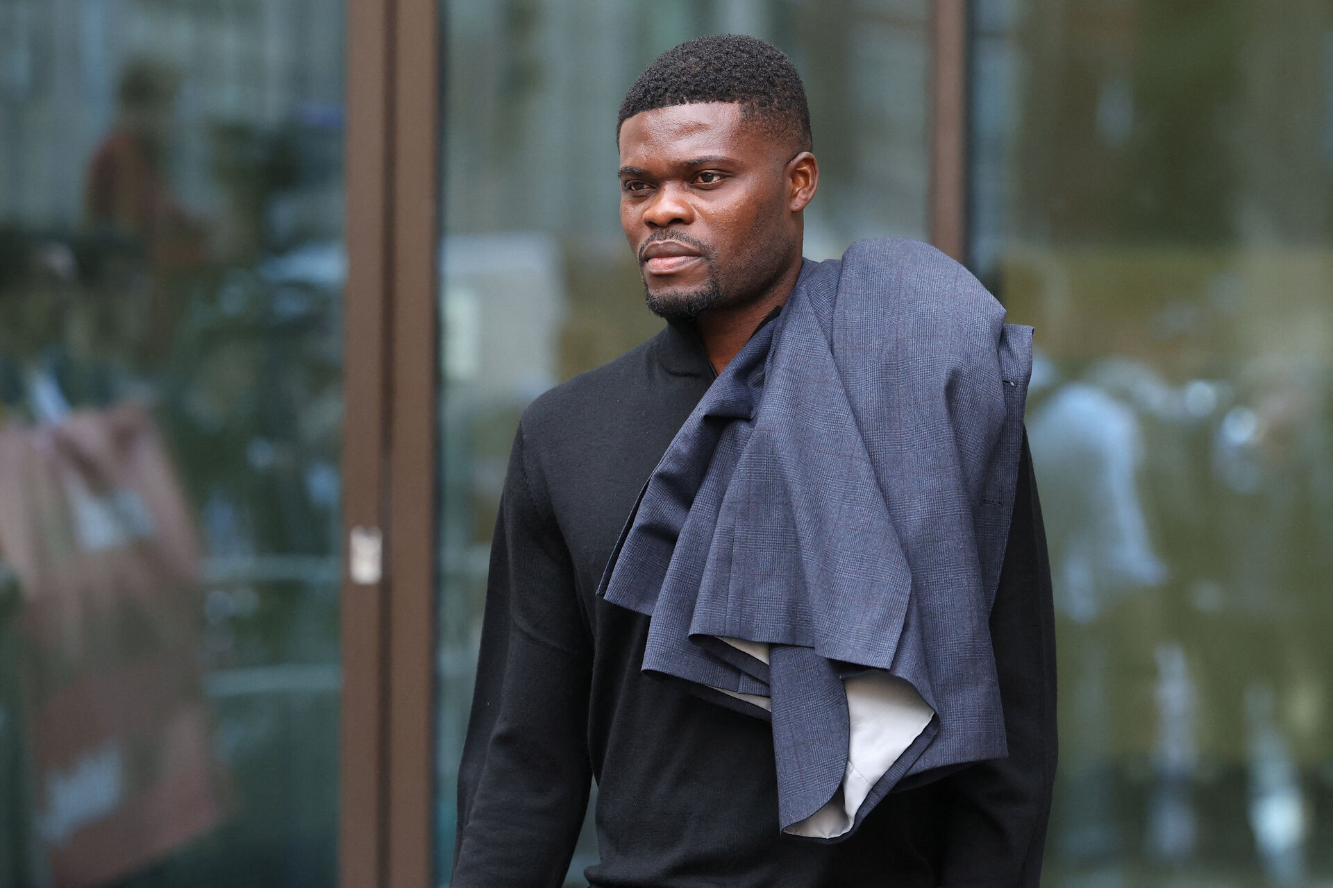 Thomas Partey ankommer til retten i London med en jakke over skulderen.