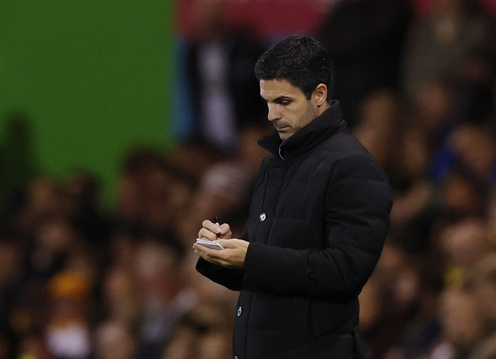 Mikel Arteta står og tager notater.