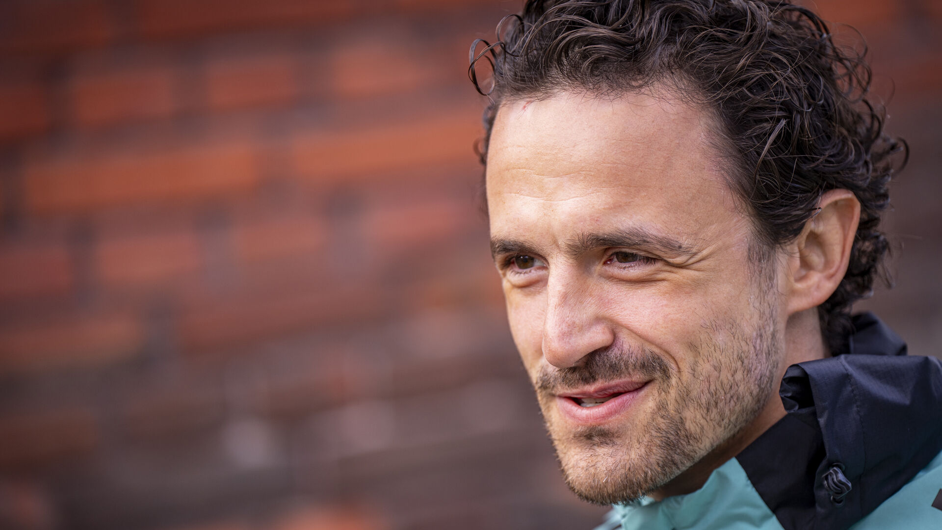 Thomas Delaney står foran en murstensmur