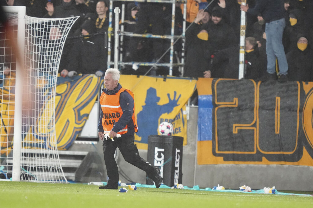 En vagt fjerner nogle bamser, nogle Brøndby-fans har smidt på banen.