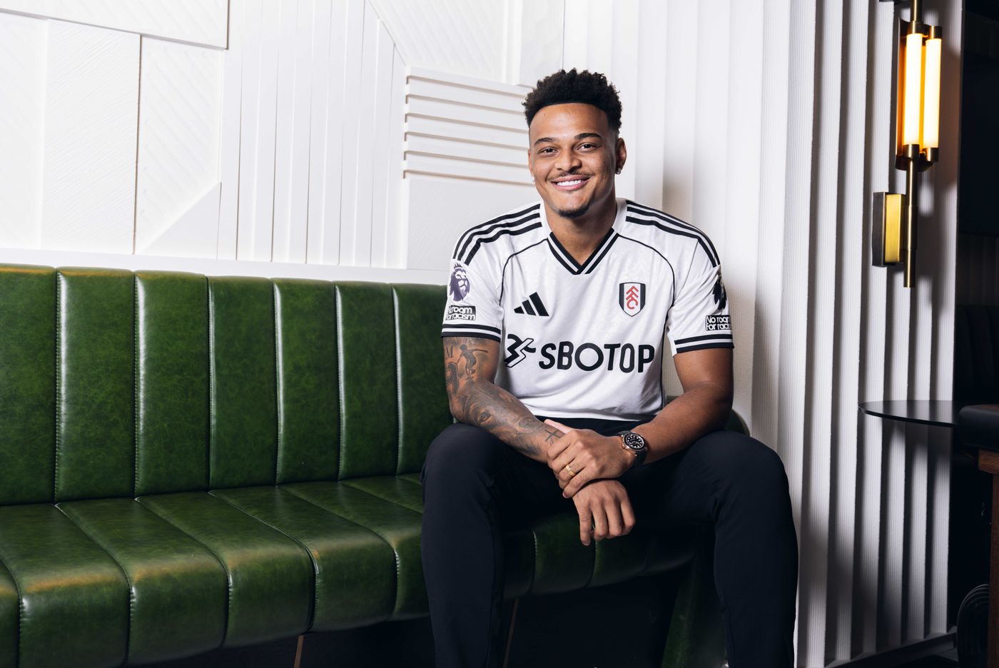 Rodrigo Muniz sidder på en grøn sofa og smiler.