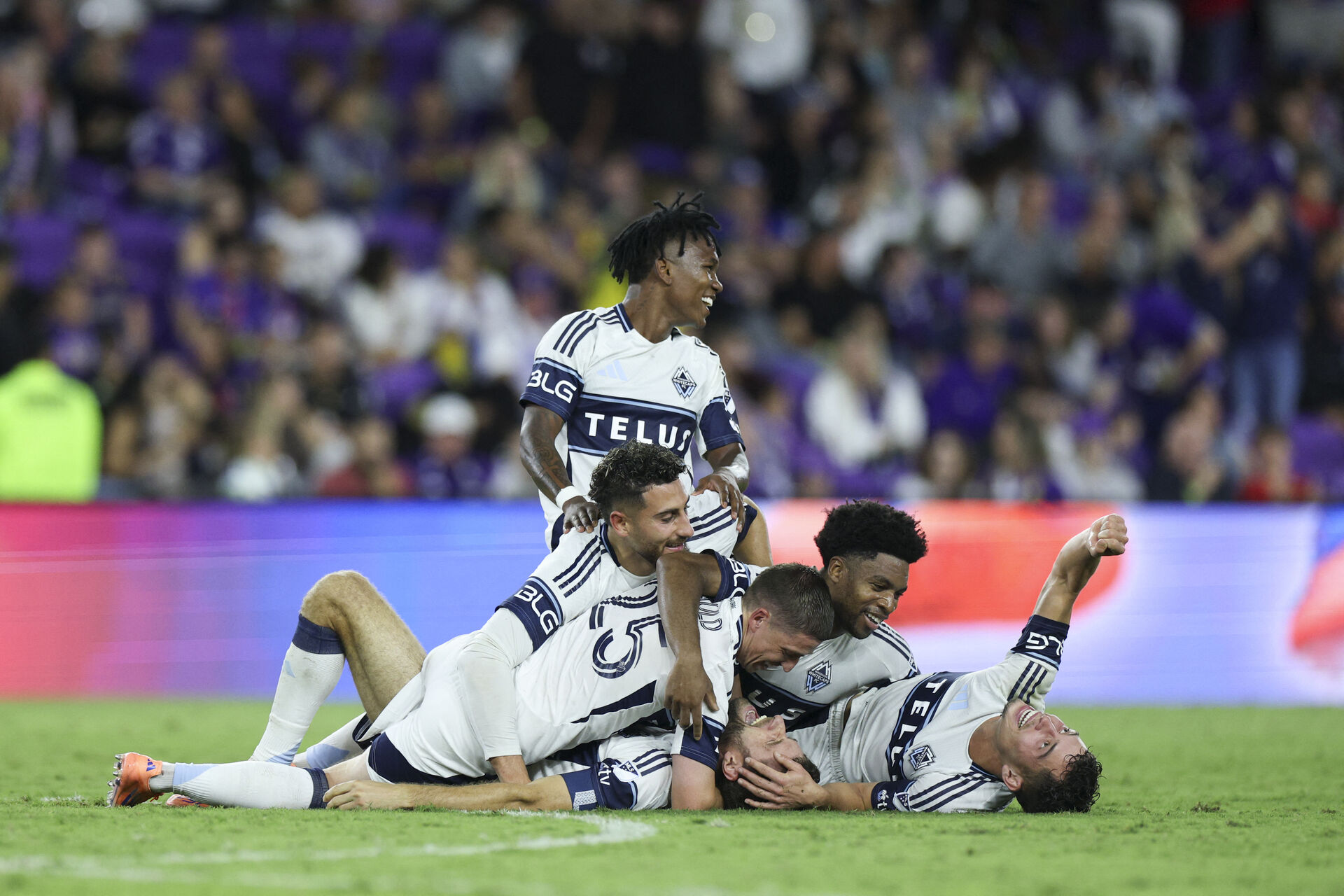 Vancouver Whitecaps-spillere ligger i en klynge og jubler.