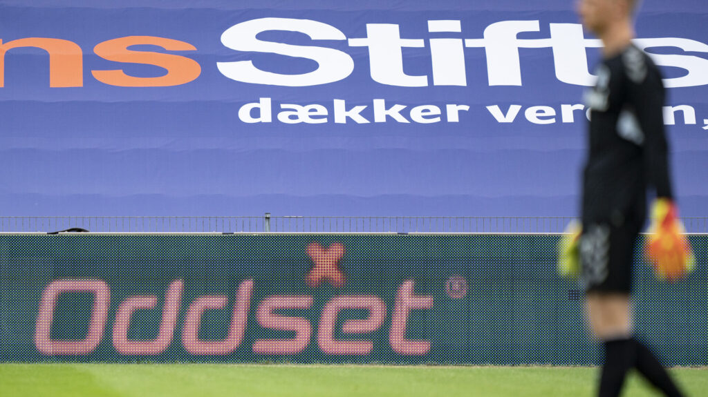 Oliver Christensen med en spilreklame i baggrunden