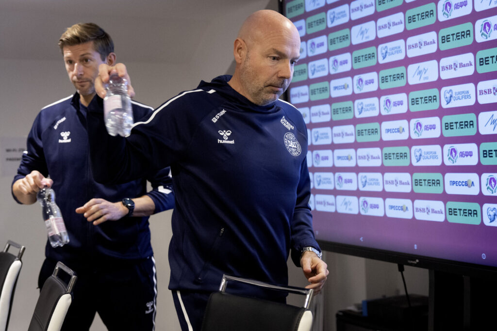 Brian Riemer med en vanddunk i hånden på et pressemøde.