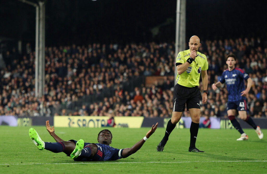 Bukayo Saka ligger på græsset og slår ud med armene.