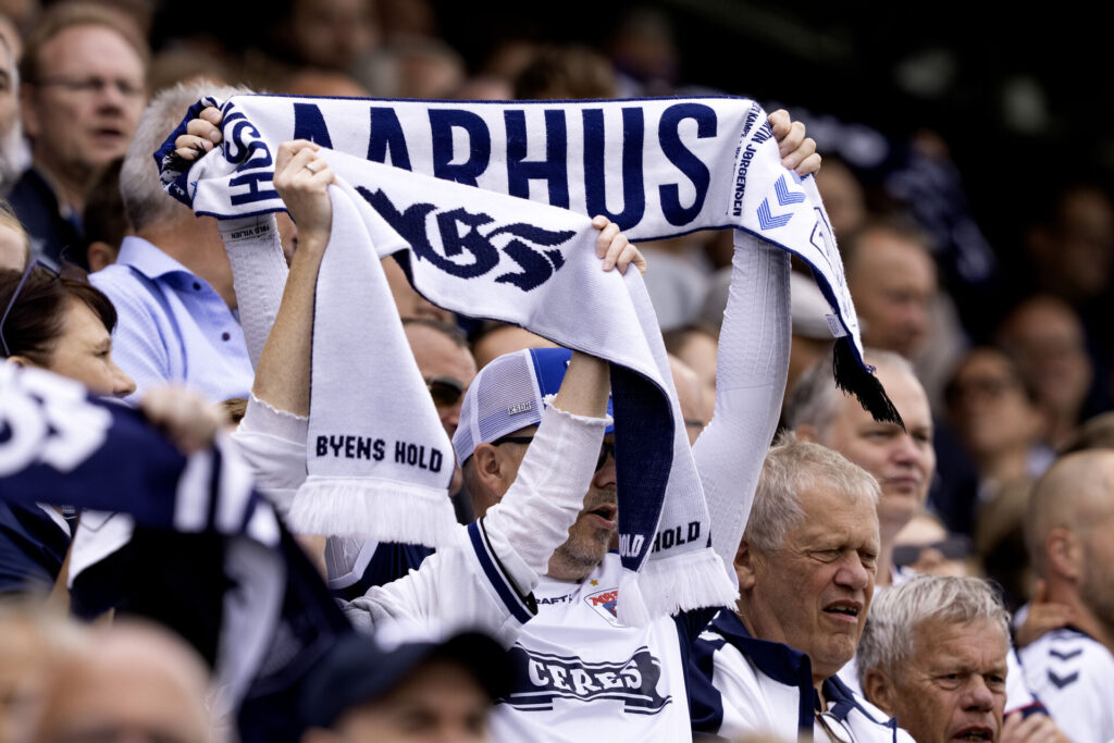 En fan løfter et halstørklæde, hvor der står Aarhus på.
