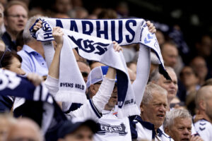 En fan løfter et halstørklæde, hvor der står Aarhus på.