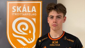 Simon Jørgensen i Skálas trøje foran klublogo