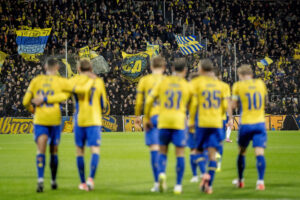 Brøndby-truppen går sammen med fans i baggrunden.