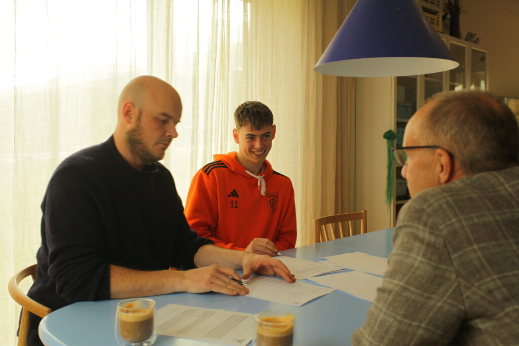 Simon Jørgensen sidder indedøre og underskriver kontrakt med andre personer